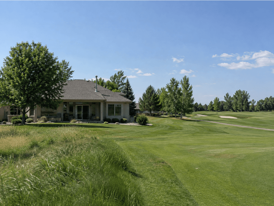 Single-story home with a covered back patio and large windows overlooking a golf course fairway